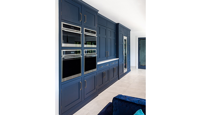Floor-to-ceiling cabinetry provides storage space and blends with a bank of Caple ovens