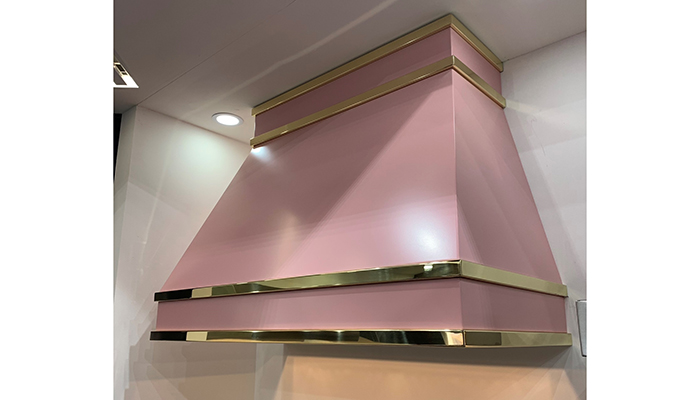 A bespoke wall-mounted hood painted in Farrow & Ball's Nancy Blushes with mirror polished brass detail