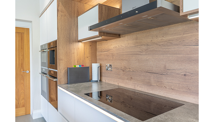 The colour of the wood warms the cool white cabinetry, and is seen alongside Neff induction hob and hood