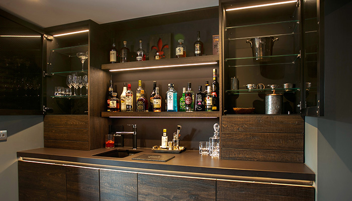 Rich, industrial-style Zerox furniture by Rotpunkt creates a subtle contrast in this custom bar area. The glass storage cabinets provide ample storage for glassware and are designed with a unique mesh-style glass finish on the doors. Above the 50mm-thick made-to-measure Dekton worktop sits a practical wall panel system by Rotpunkt