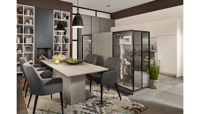 Mid-height units in Vicenza Oak woodgrain are flanked by back-to-back glass display cabinets, which create a subtle divide in this handleless kitchen featuring furniture from Pronorm’s Y-Line and Proline ranges