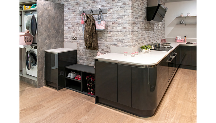 Crown Imperial showcases a dedicated boot and utility room set at its Daventry showroom, highlighting the importance of organised storage, including its space-saving laundry unit innovation. The laundry unit is styled in Zeluso Rock Grey and the boot room space in Furore gloss Graphite, while curved units add a seamless connection between the utility and main kitchen