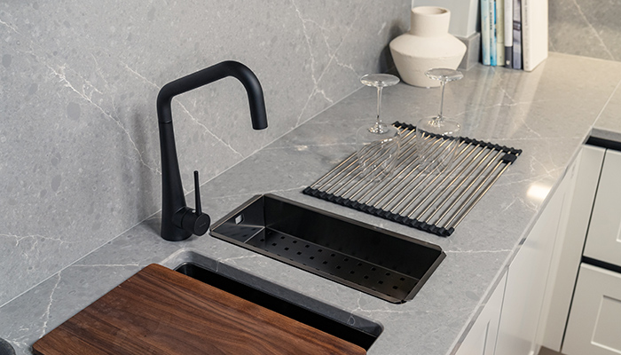 The Monarch Kombino 20 & Kombino 10 sinks shown in Anthracite, with an Anthracite strainer, Walnut chopping board and all-round drying rack, with the Eden tap in Black