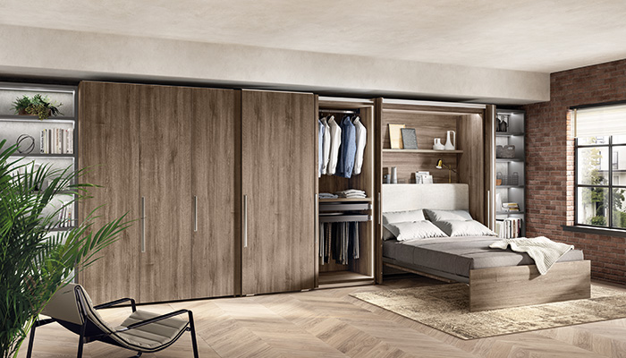 Designed by Rainlight Studio in collaboration with Scavolini, the BoxLife furniture pictured includes pocket panelled doors, in Garden Walnut textured melamine, that conceal or reveal a pull-down bed, wardrobe storage and a desk area