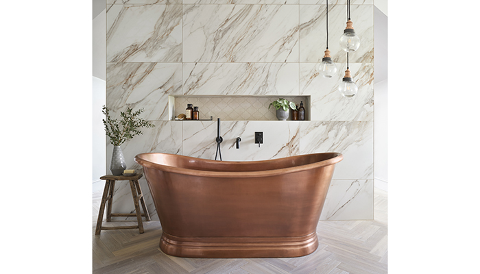 The intricate veining of these Corinto marble-effect large-format wall tiles in a design by Ripples Bathrooms creates a beautiful statement wall behind a copper freestanding bath with Arabesque marble mosaic tiles in the alcove