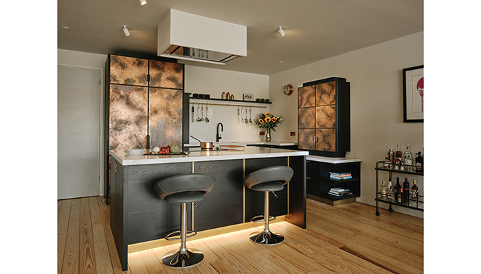 Patinated copper cabinetry is the star of this compact kitchen in Rotherhithe and suits the industrial nature of the converted warehouse where the apartment is located