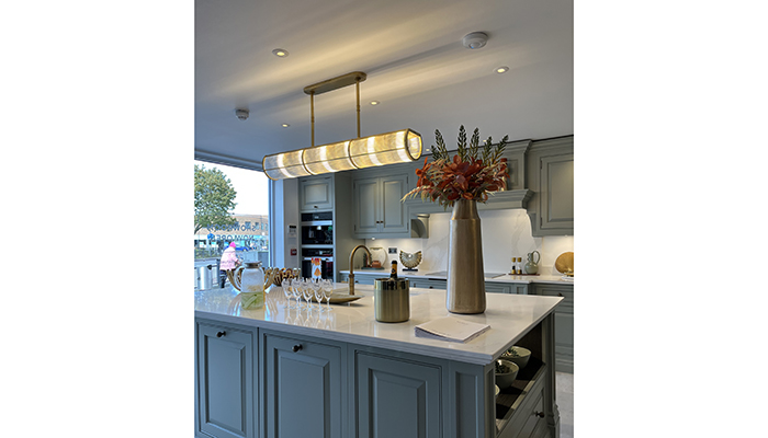 Adding a touch of glamour and complementing the elegant design of Tom Howley’s new Nottingham showroom, the Ralph Lauren Allen Medium Linear Pendant has a Natural brass and ribbed glass finish. It sits above a kitchen island, painted in Moonshine, from the retailer’s Devine collection