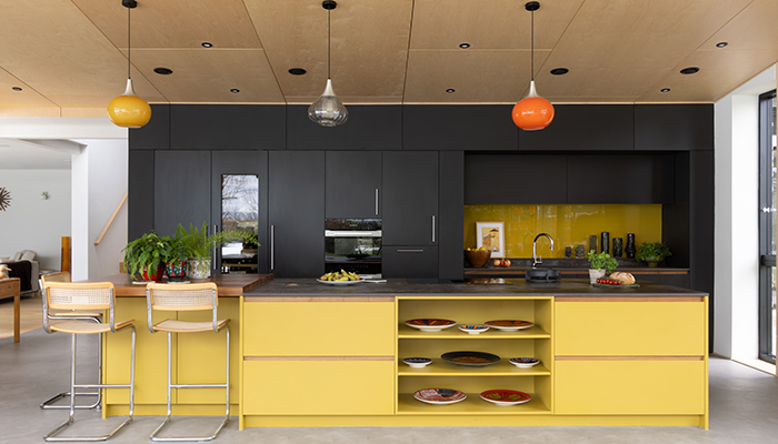 The colours of the three vintage glass pendant lights by iconic Danish brand Holmegaard complement the Grapefruit 302 paint by Finnish brand Tikkurila, used for the island below in this mid-century modern-style kitchen by Searle & Taylor