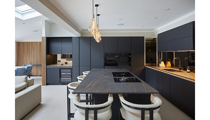 Drawing the eye and adding an industrial touch to this dark kitchen designed by Sheraton Interiors, the three Veroni pendant lights by Tala are positioned above the island to provide task and mood lighting 
