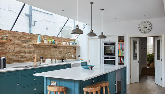 Adding an industrial edge to this traditional-style kitchen by The Main Company, these metal pendant lights from Mullan co-ordinate seamlessly with the silver hardware and brick feature wall – photo by Chris Snook