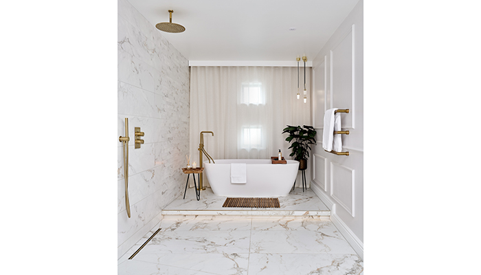 This project by Ripples offers a carefully curated sense of indulgence, featuring its freestanding bath with silk matt finish in Polished White, freestanding bath mixer, ceiling-mounted shower arm and shower head all in brushed brass, and marble-effect porcelain tiles