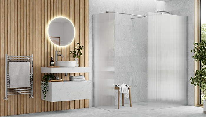 Bathrooms to Love by PJH’s Natural wall-hung furniture range is seen here in a white marble-effect finish on the 800mm basin shelf and drawer unit. It is paired with the Luxey round washbasin and RefleXion Iconix Fluted Wetroom Panel