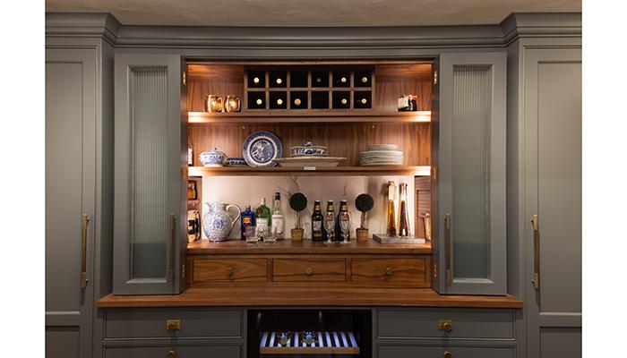 On the lower ground floor is a Classic, Georgian bespoke walk-in pantry with walnut internals. To the left is an integrated tall freezer with internal ice maker, to the right is an integrated fridge, and at the centre is a wine fridge, all by Liebherr. It features reeded glazed doors that fold back on themselves