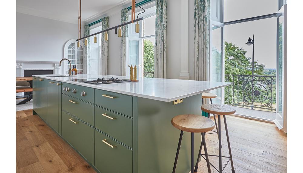 This project by Kitchens by Holloways features island cabinetry painted in Mylands' Brompton Road No.205, complemented by the Statuario worktops and wooden planked flooring adding texture and warmth to the room