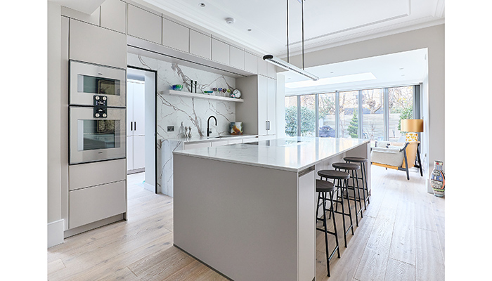 A timeless kitchen design by Kitchens by Holloways using its Linear range of cabinets paired with a Palermo quartz stone worktop and contrasting splashback feature wall