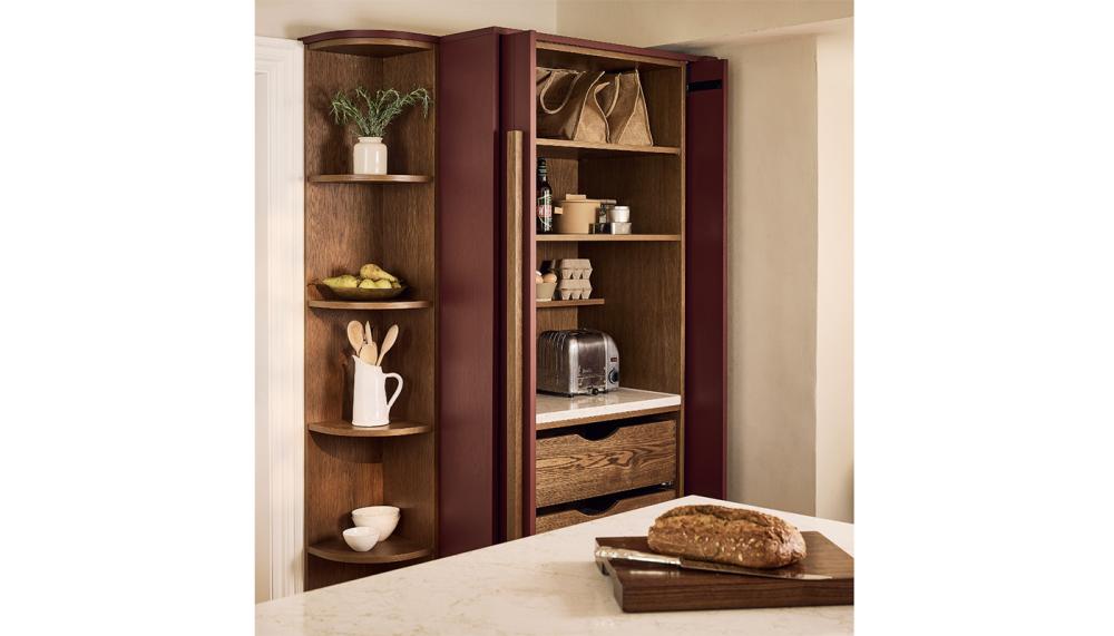 The Madingley Kitchen by Naked Kitchens features a red pantry cupboard with pocket doors that open to reveal everything the household needs for breakfast