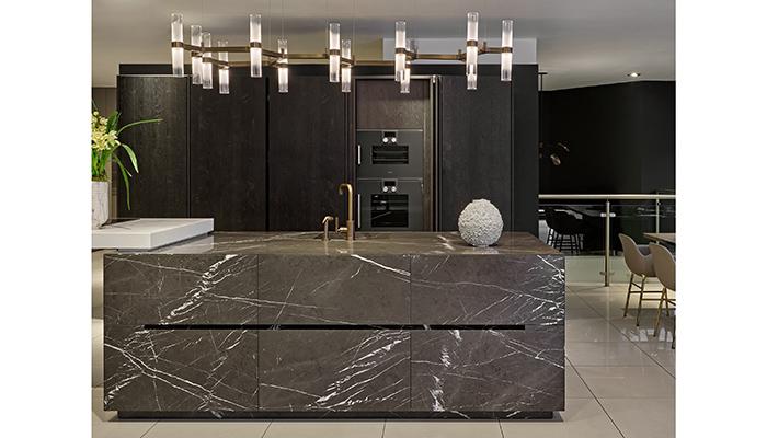 Eggersmann Unique stone island in front of Oak veneer tall cabinets with Gaggenau appliances, behind pocket doors